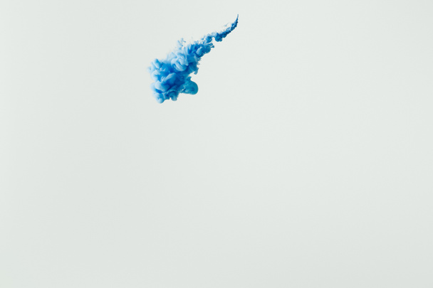 Nahaufnahme von leuchtend blauem Farbspritzer im Wasser isoliert auf grau - Foto, Bild