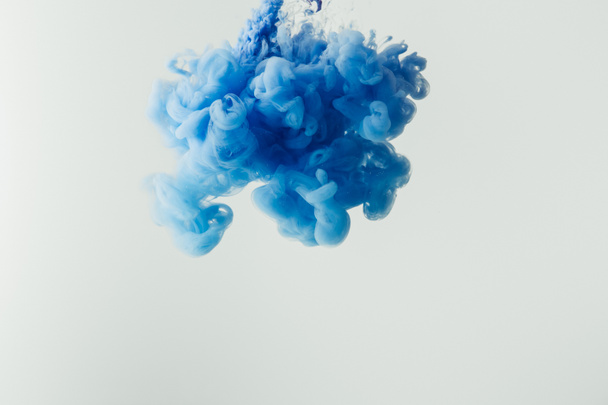 primo piano colpo di spruzzata di vernice blu brillante in acqua isolata su grigio
 - Foto, immagini