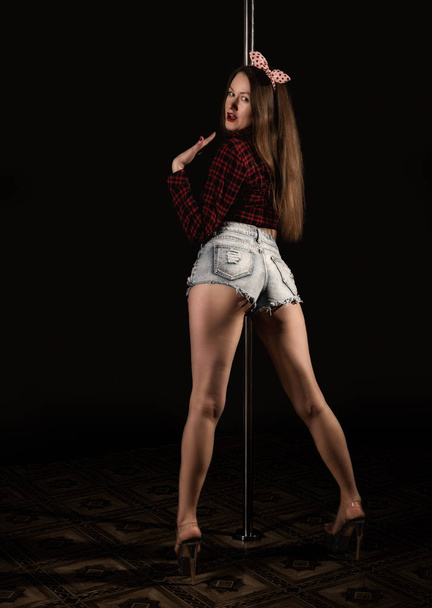 beautiful go-go dancer in denim shorts and checkered shirt in night club. Pole Dance pin-up girl - Foto, imagen