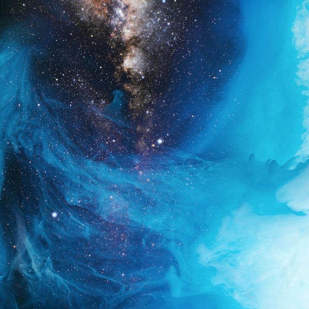 full frame beeld van het mengen van de blauwe en zwarte verf spatten in water met universum achtergrond - Foto, afbeelding
