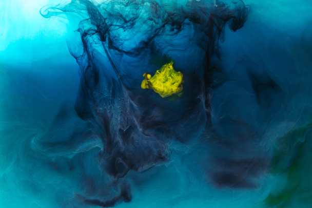 full frame image of mixing of blue, black, yellow and green paints splashes in water - Photo, Image