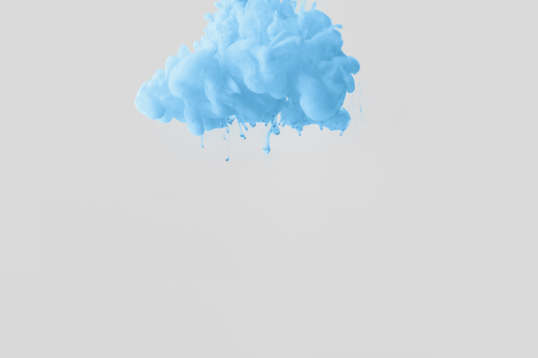 Nahaufnahme heller blassblauer Farbspritzer im Wasser isoliert auf grau - Foto, Bild