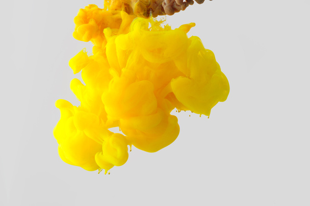 Close up view of bright yellow ink
 splash in water isolated on gray - Photo, Image