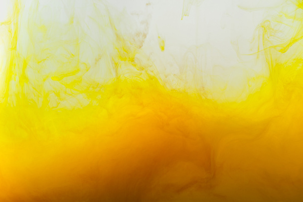 primer plano vista de fondo con mezcla de pinturas amarillas y marrones salpicaduras en el agua
 - Foto, imagen