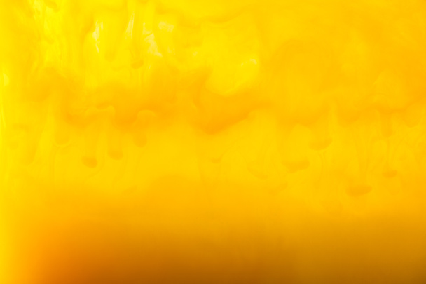 full frame image of mixing of yellow and brown paints splashes in water - Foto, Imagem