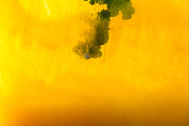 πλήρης εικόνα καρέ ανάμειξης κίτρινες και πράσινες μπογιές πιτσιλιές στο νερό - Φωτογραφία, εικόνα