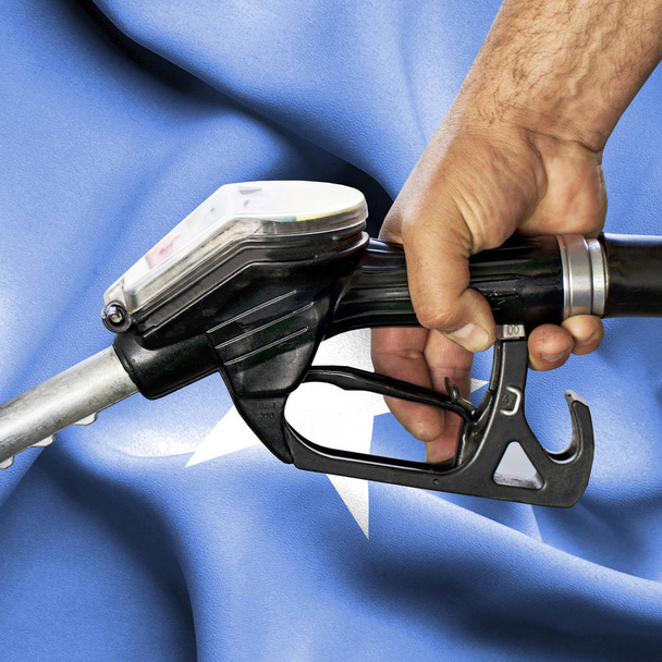 Benzinverbrauchskonzept - Handhalteschlauch gegen Fahne - Foto, Bild