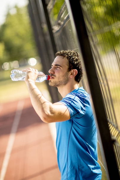 Handsome yung man drinking water from the bottle outdoors - Foto, Imagem