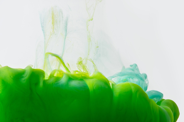 close up view of mixing of green and bright turquoise paints splashes in water isolated on gray - Photo, Image