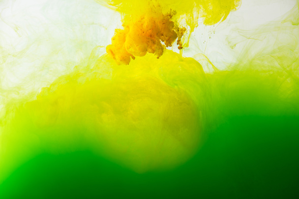 vista de cerca de la mezcla de pinturas verdes y amarillas salpicaduras en agua aislada en gris
 - Foto, imagen
