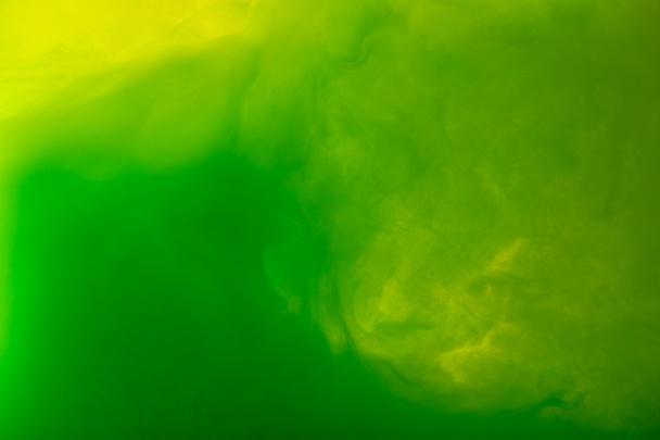 full frame image of mixing of green and yellow paints splashes in water isolated on gray - Photo, Image