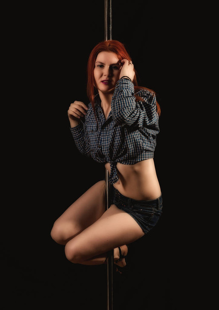beautiful go-go dancer in denim shorts and checkered shirt in night club. Pole Dance pin-up girl - Photo, Image