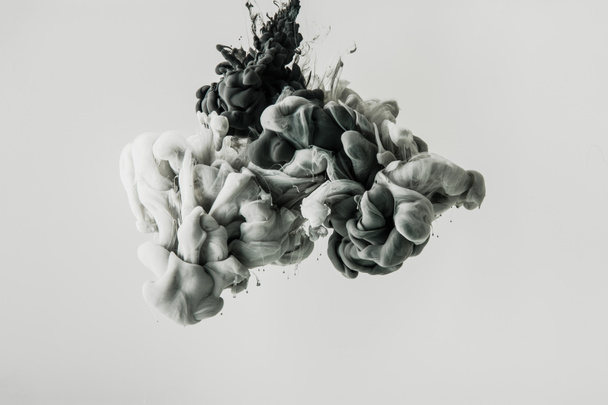 Close-up van het mengen van licht grijze en zwarte verf spatten in water geïsoleerd op grijs - Foto, afbeelding