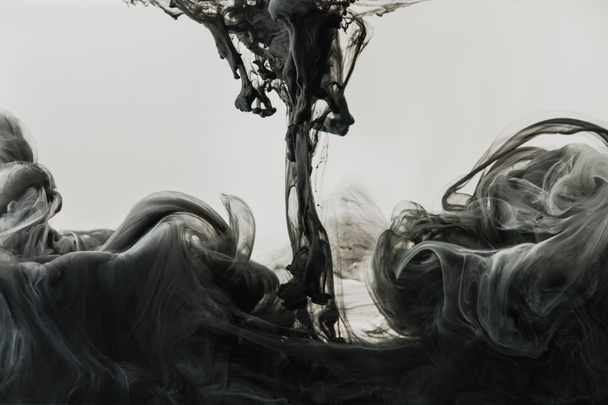 Visão de perto de mistura de tinta cinza-clara e preta em água isolada em cinza
 - Foto, Imagem