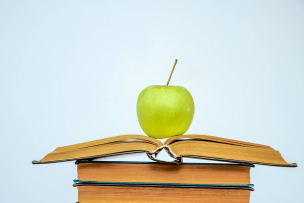 Open book on a pile of books and green apple isolated on white background. healthy food and education. back to school idea - Foto, Imagen