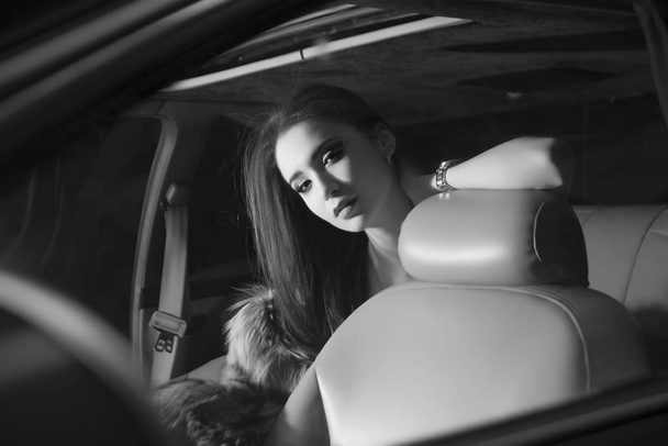 Young brunette woman sitting in luxury car - Фото, зображення