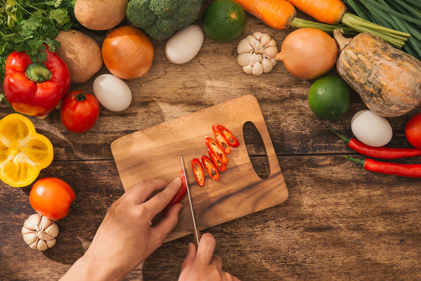 Vágó piros chili. Férfi kezét a konyhában főzés zöldség-saláta. Szemközti nézet. - Fotó, kép