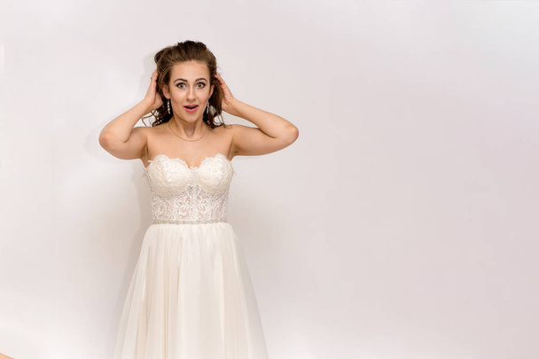 beautiful bride in white wedding dress in different poses on white backgrounds shows different emotions - Fotó, kép