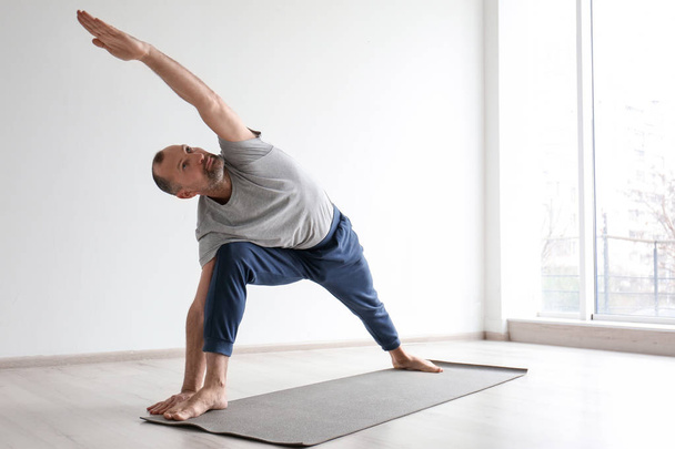 Sporty man practicing yoga indoors - Foto, Imagem