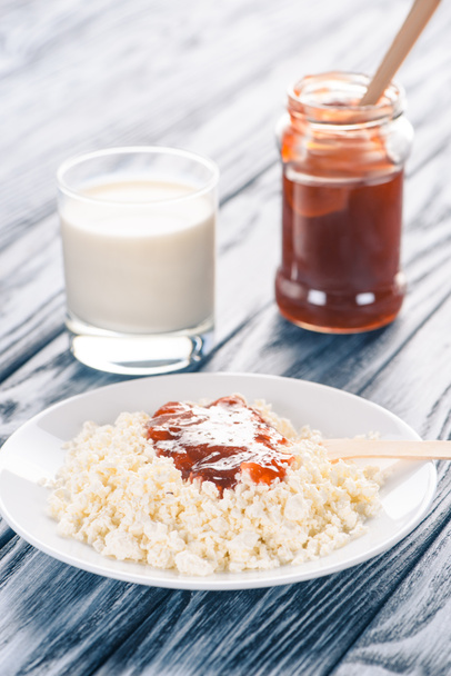 close-up view of delicious cottage cheese with jam and glass of milk on wooden table  - 写真・画像