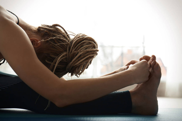 Young woman practicing yoga indoors - Фото, изображение