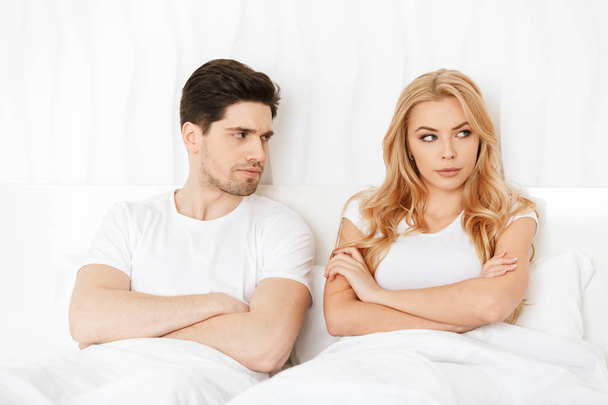 Angry loving couple lies in bed indoors at home quarrel. - Фото, изображение
