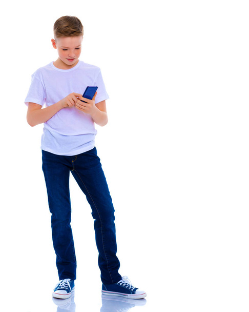 A little boy uses a mobile phone. - Foto, afbeelding