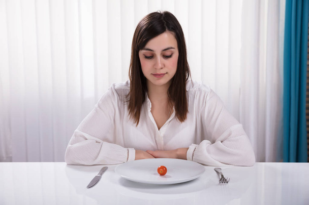 Young Woman Sitting With Plate Of Cherry Tomato At Breakfast - Foto, immagini