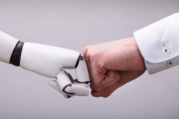 Robot And Human Hand Making Fist Bump On Grey Background - 写真・画像