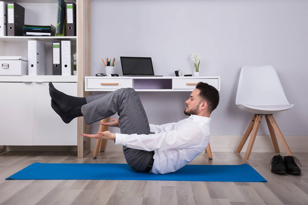 Side View Of A Businessman Doing Exercise On Exercise Mat - Photo, image