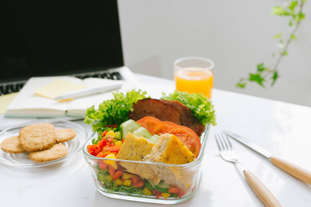 Еда в офисе. Здоровый обед для работы со свежим салатом и апельсиновым соком
 - Фото, изображение