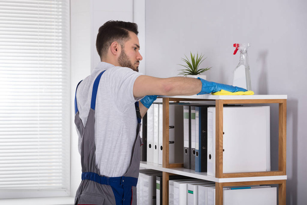 Close-up Of A Young Male Cleaner Cleaning Shelf At Workplace - Fotoğraf, Görsel