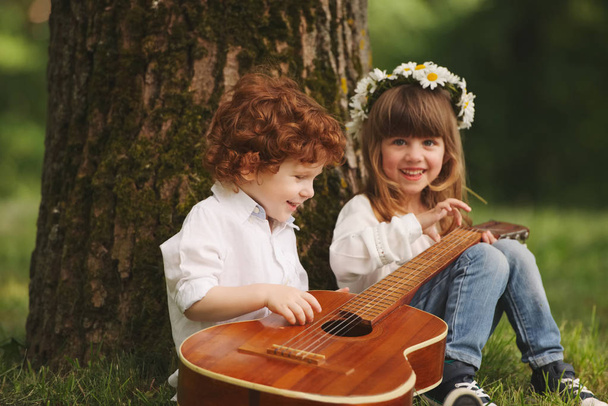 boy and girl playing guitar in summer park - Fotoğraf, Görsel