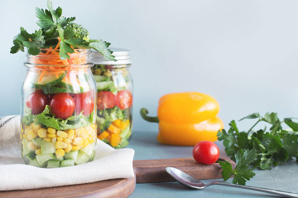 Vegetable healthy homemade colorful salad in mason jar with tomato, lettuce, broccoli on blue. Copy space. Lunch for work. - Φωτογραφία, εικόνα
