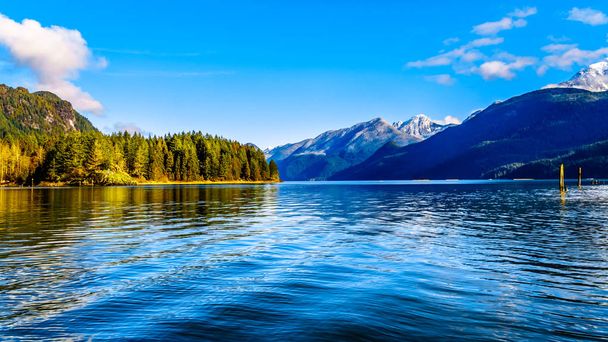 Озеро Питта с заснеженными павлинами Золотых Ушей, Тингл Пиком и другими горными павлинами окружающего Берегового горного хребта в долине Озер Британской Колумбии, Канада
 - Фото, изображение