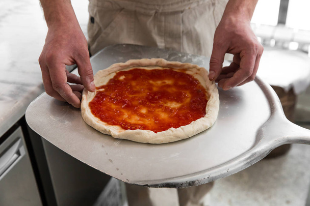 Fresh original Italian raw pizza, preparation in traditional style. Hands of chef baker making pizza at kitchen. - Valokuva, kuva