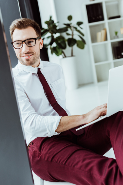 handsome smiling businessman in eyeglasses using laptop - Photo, image