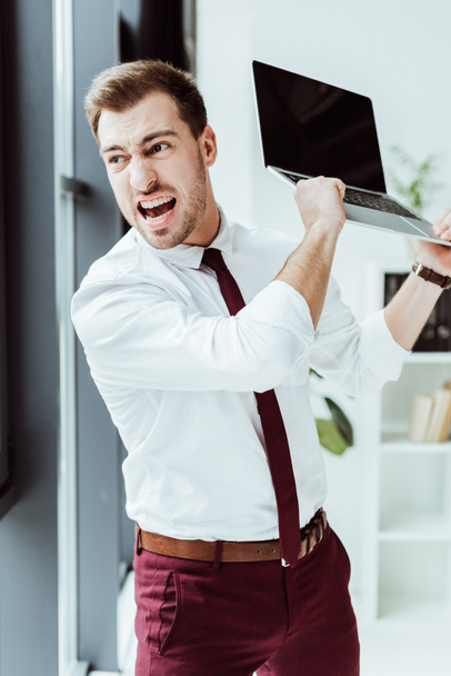 aggressive businessman yelling and throwing laptop in office - Foto, Imagen