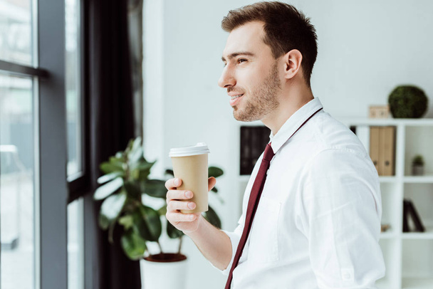 бізнесмен тримає одноразову чашку кави і дивиться на вікно
 - Фото, зображення