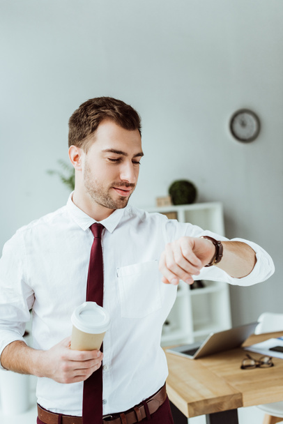 Geschäftsmann mit Einwegbecher Kaffee schaut auf Armbanduhr - Foto, Bild