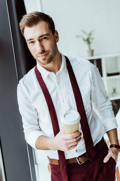 handsome businessman with disposable cup of coffee in office - Zdjęcie, obraz