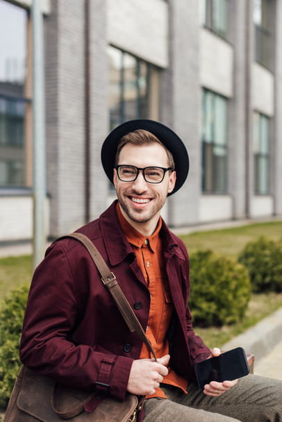 handsome cheerful man with bag using smartphone - Foto, Bild