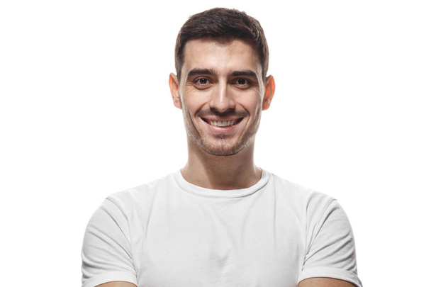 Detailní záběr ať se usmívám pohledný muž v bílém tričku, při pohledu na fotoaparát, izolované  - Fotografie, Obrázek