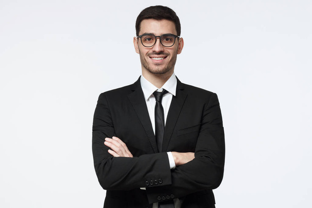 Portrait of smiling handsome business man standing with crossed arms isolated on grey background - Foto, Bild