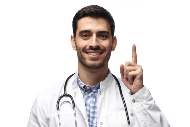 Attractive young man doctor pointing up with his finger isolated on white background - Photo, Image