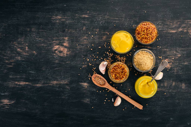 Assortment of mustard in sauces. Spices On a black wooden background. Top view. Copy space for your text. - Foto, Bild