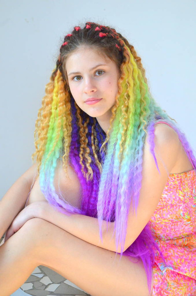 Una chica con un pelo largo y ondulado pintado en colores arcoíris. Pelo túnica kanekalon
 - Foto, Imagen