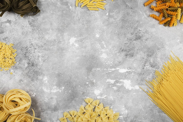 Various raw pasta on gray background. Top view, copy space. Food - Photo, Image