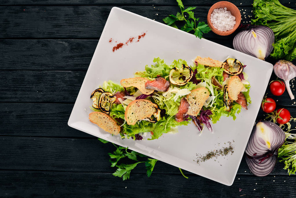 Caesar salad with salmon. Top view. On a wooden background. Copy space. - Zdjęcie, obraz