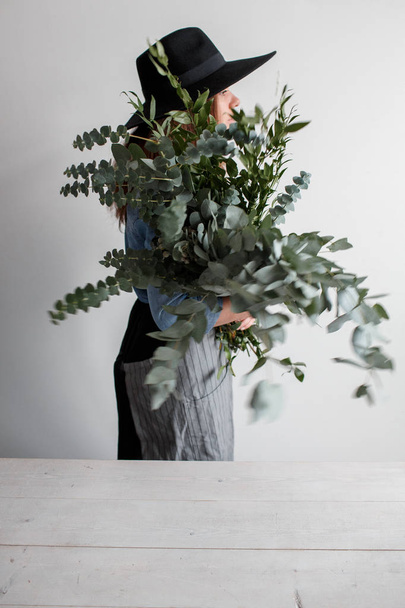 Florist makes a bouquet. Process of work. woman holding a bouquet of eucalyptus in hands - Photo, image